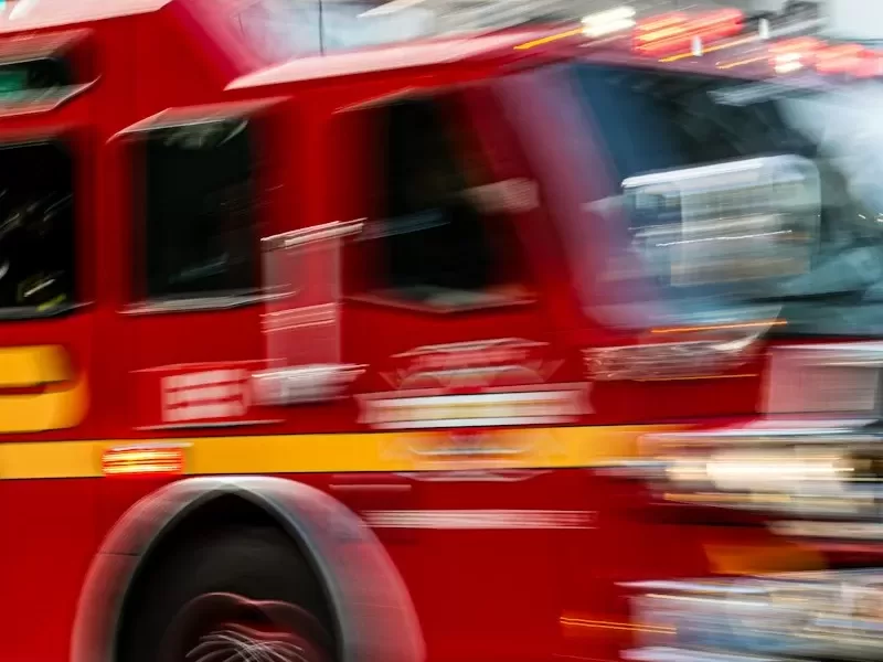 a red fire truck driving down a street next to a tall building