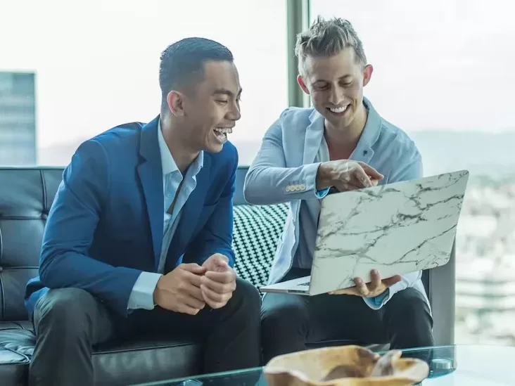 two men in suit sitting on sofa